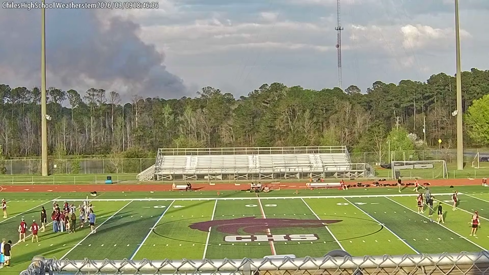 Wildfire smoke billows behind a lacrosse game